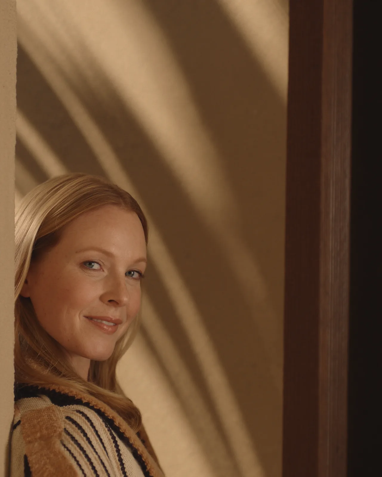 Woman leaning in a sunlit doorway with even skin tone, for BBL® HEROic™ broadband light at Palm Lux Aesthetics in Palm Beach Gardens